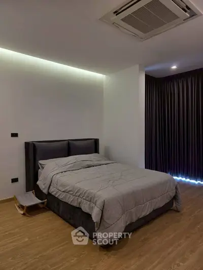 Modern bedroom with sleek design and cozy ambiance, featuring a comfortable bed and elegant lighting.