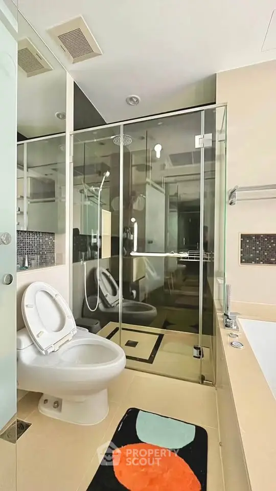 Modern bathroom with glass shower, bathtub, and stylish decor