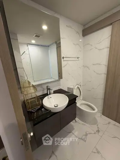 Modern bathroom with sleek design, featuring a stylish sink and elegant marble tiles.