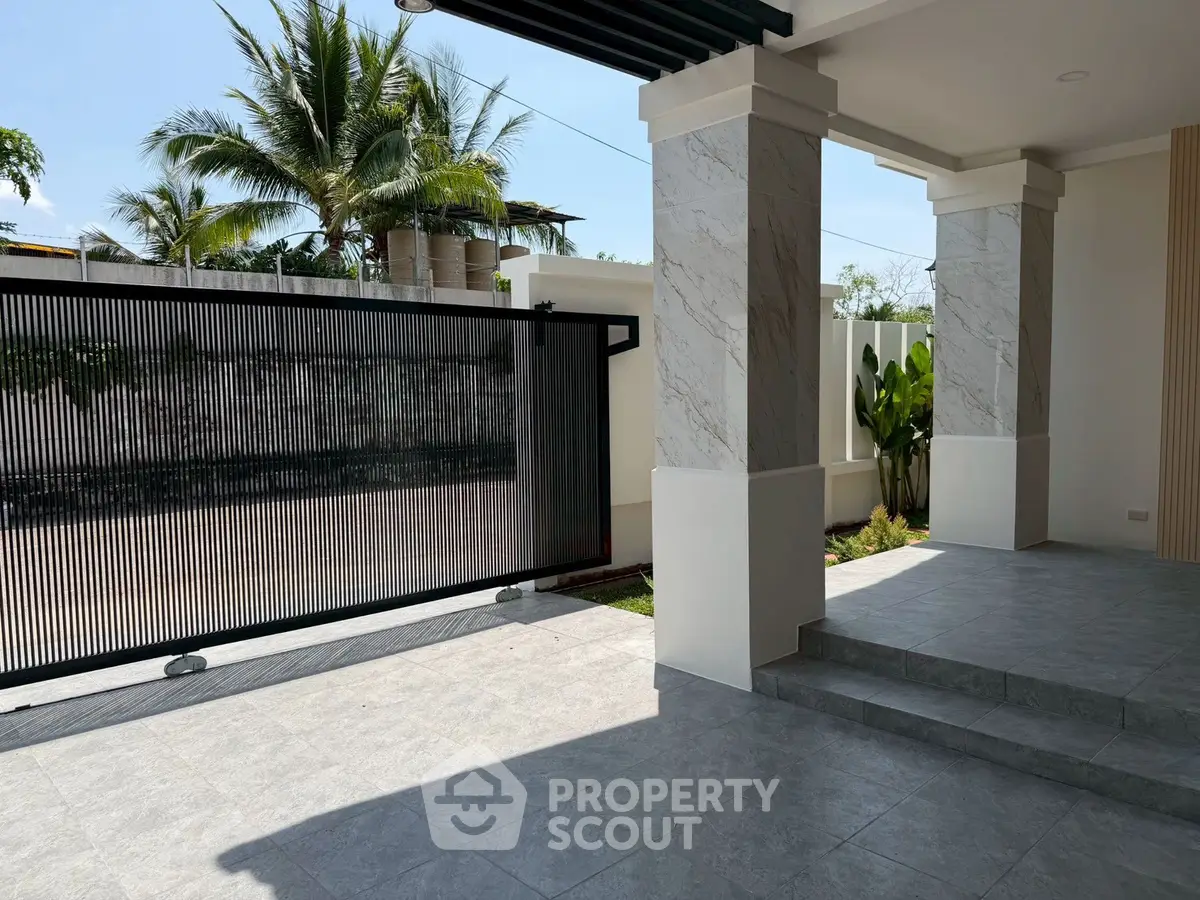 Modern home entrance with sleek gate and tropical landscaping
