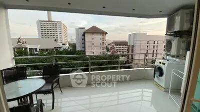 Spacious balcony with outdoor seating and city view, featuring washing machine and air conditioning units.
