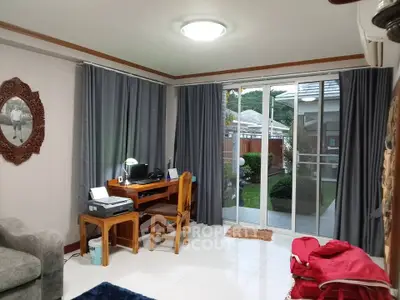 Cozy living room with garden view, featuring a study desk and sliding glass doors leading to a lush backyard.