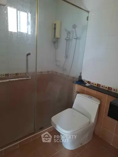 Modern bathroom with glass shower enclosure and sleek toilet design.