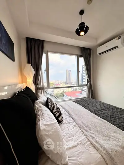 Modern bedroom with city view, featuring stylish decor and large window for natural light.