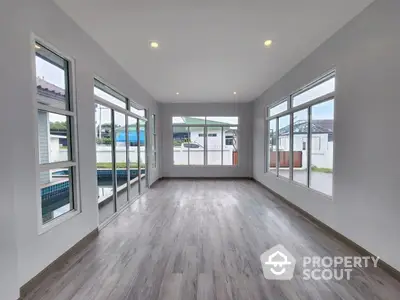 Spacious and bright living room with large windows, modern lighting, and elegant wood flooring, perfect for family gatherings and entertainment.