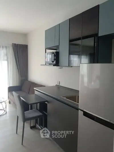 Modern compact kitchen with sleek cabinetry and integrated appliances in a cozy apartment setting.