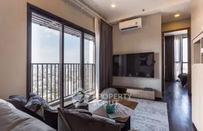 Modern living room with city view, large TV, and stylish decor in high-rise apartment.