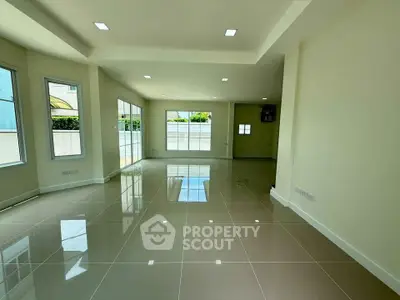 Spacious open-plan living area with glossy tiled floors and abundant natural light.