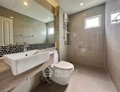 Modern bathroom with sleek fixtures and large mirror in a contemporary home.