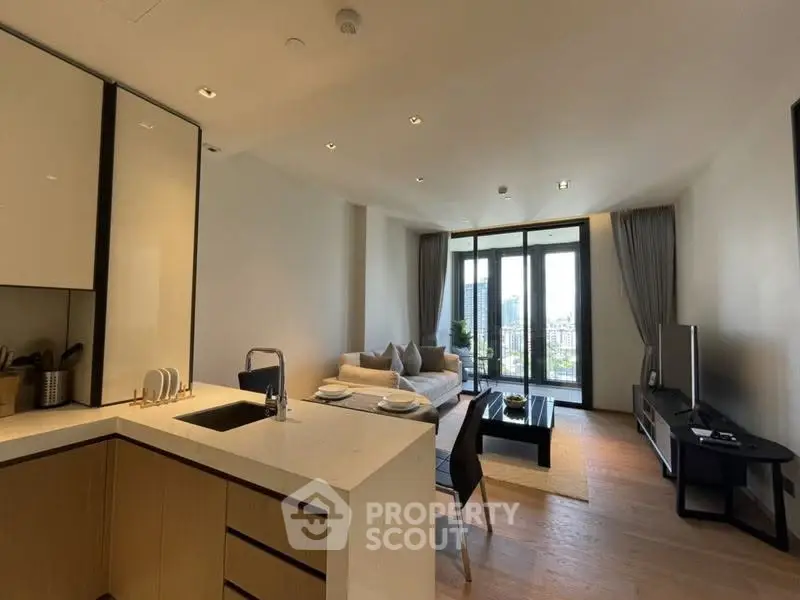 Modern open-plan living room with kitchen, featuring sleek design and city view balcony.