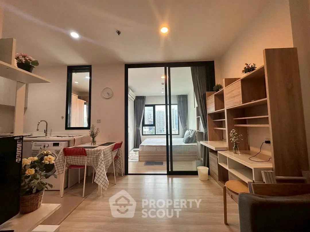 Modern open-plan living room with kitchen and bedroom, featuring stylish decor and ample natural light.