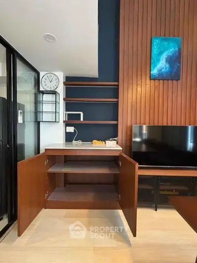 Modern living room with open wooden cabinets, sleek TV setup, and stylish wall decor.