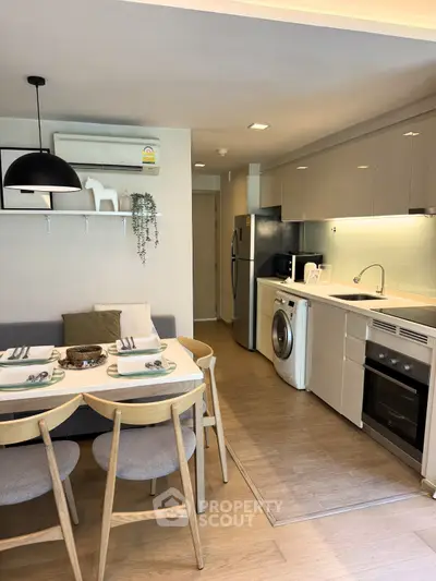 Modern kitchen with open layout, dining area, and built-in appliances in a stylish apartment.