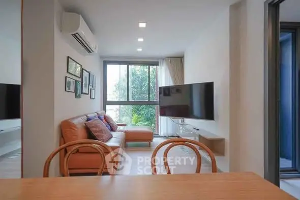 Modern living room with stylish decor and large window offering natural light.