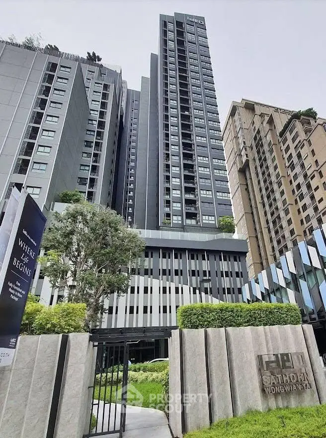 Modern high-rise building with lush greenery and sleek architecture in urban setting.