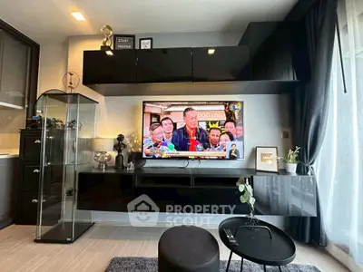 Modern living room with sleek black cabinetry and large TV, featuring stylish decor and natural light.