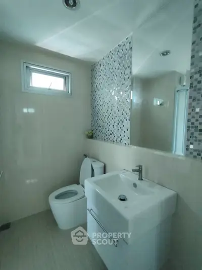 Modern bathroom with sleek fixtures and mosaic tile accent wall