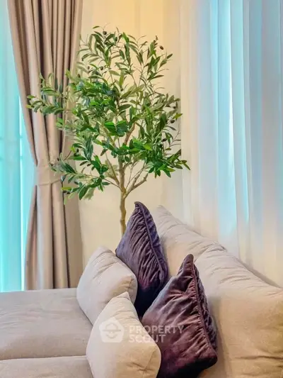 Elegant living room with plush sofa and lush indoor plant, creating a cozy and inviting atmosphere.