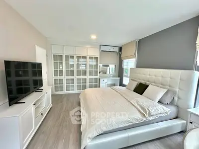Spacious modern bedroom with elegant white furniture and large windows for natural light.