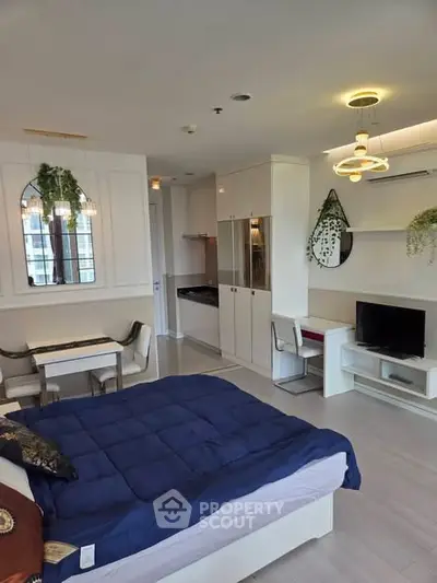 Modern studio apartment with open layout, featuring a cozy bed, dining area, and stylish kitchen.