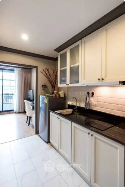 Modern kitchen with sleek cabinetry and open layout leading to dining area.