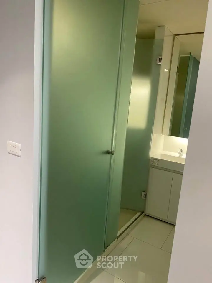 Modern bathroom with frosted glass door and sleek white fixtures