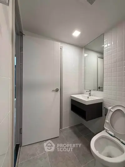 Modern bathroom with sleek fixtures and minimalist design, featuring a wall-mounted sink and contemporary tiling.