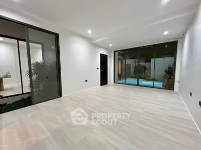 Spacious modern living room with pool view and sleek sliding glass doors.