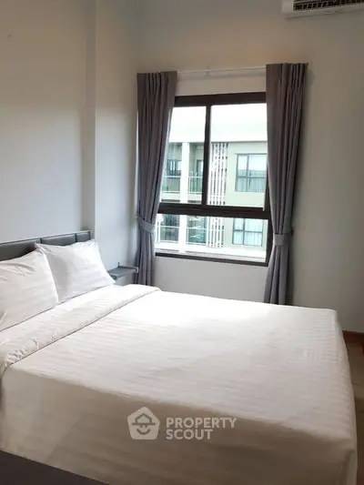 Cozy bedroom with large window and modern decor in a stylish apartment.