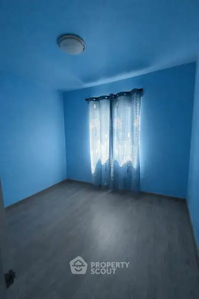 Spacious empty blue bedroom with natural light and wooden flooring