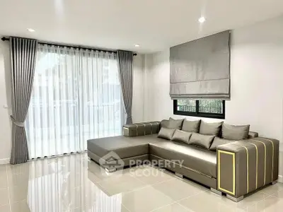 Modern living room with elegant gray sectional sofa and large window with curtains