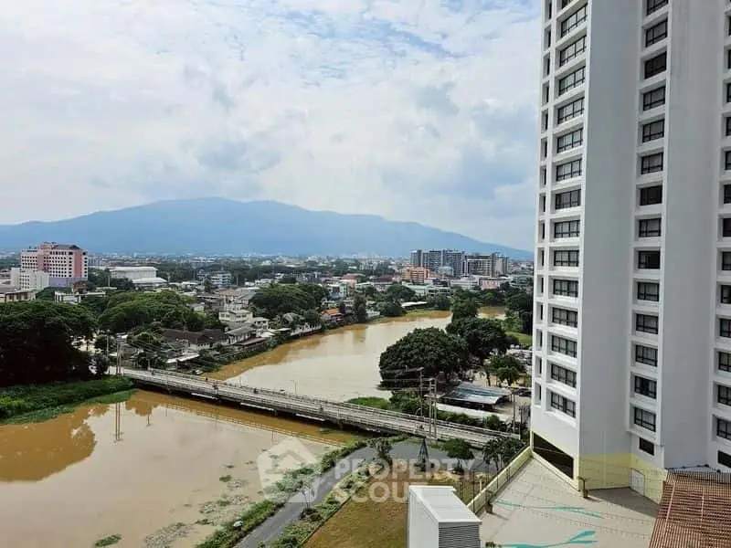 Stunning cityscape view from high-rise building overlooking river and mountains.