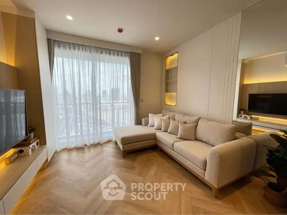 Modern living room with elegant herringbone flooring and cozy sectional sofa, featuring a large window with city view.