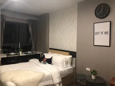 Cozy bedroom with modern decor and large window, featuring a stylish bed and wall art.