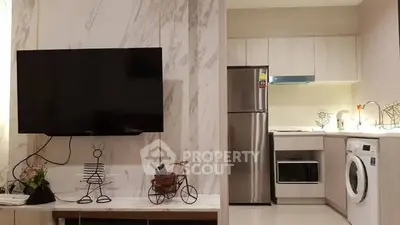 Modern kitchen with stainless steel appliances and wall-mounted TV