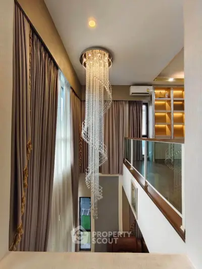 Luxurious high-ceiling living room with elegant chandelier and floor-to-ceiling curtains.
