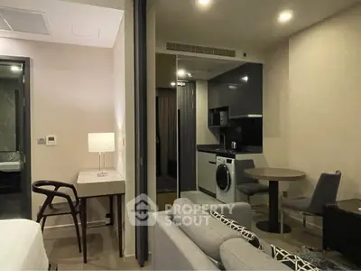 Modern studio apartment with sleek kitchen and cozy living area, featuring a washing machine and stylish decor.