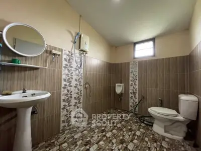 Spacious bathroom with modern fixtures and tiled walls, featuring a pedestal sink and toilet.