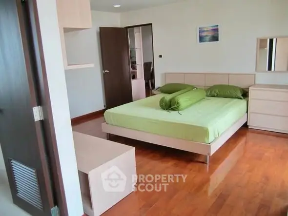 Spacious bedroom with wooden flooring and modern furniture in a stylish apartment.
