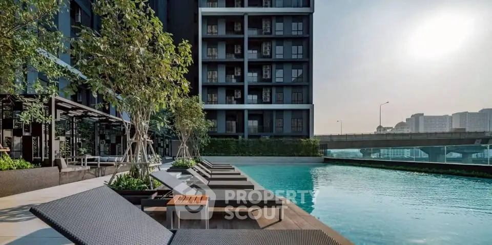 Luxurious modern apartment building with poolside relaxation area and stunning city view.