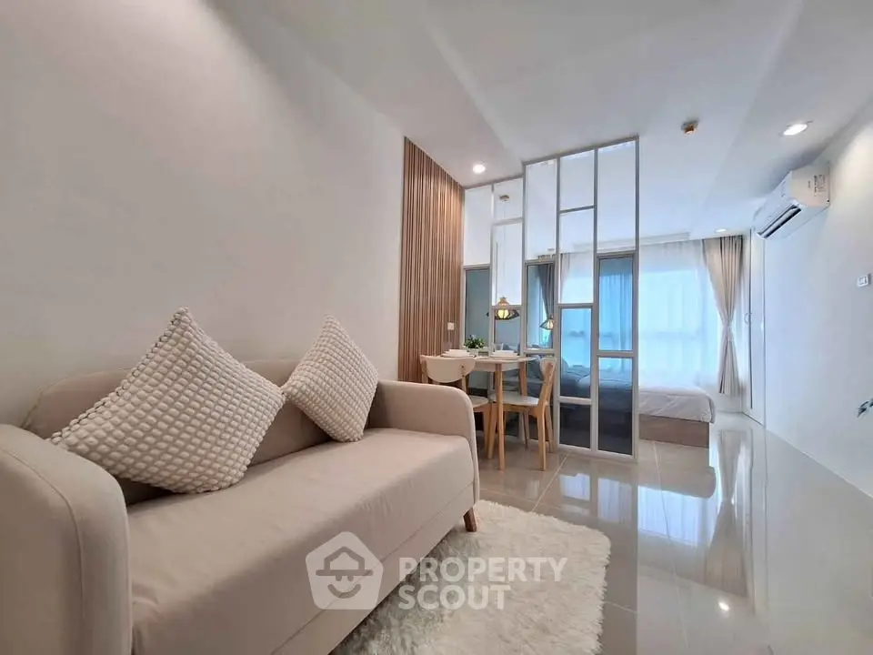 Modern open-plan living room with cozy sofa and dining area in bright apartment.