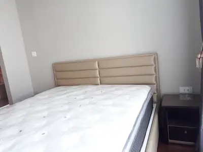 Spacious bedroom with modern bed and nightstand in a stylish apartment.