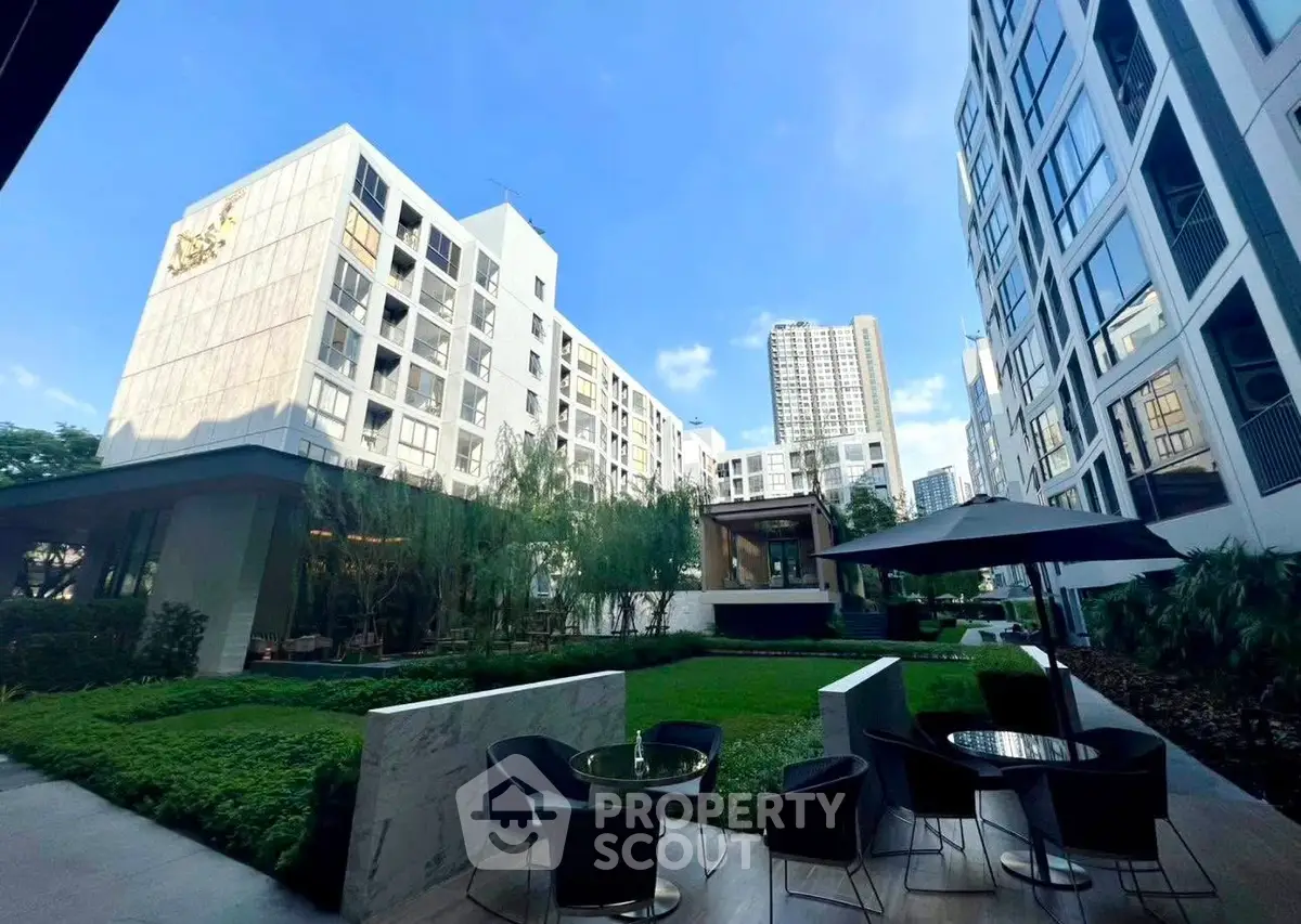 Modern apartment complex with lush garden and outdoor seating area, perfect for urban living.
