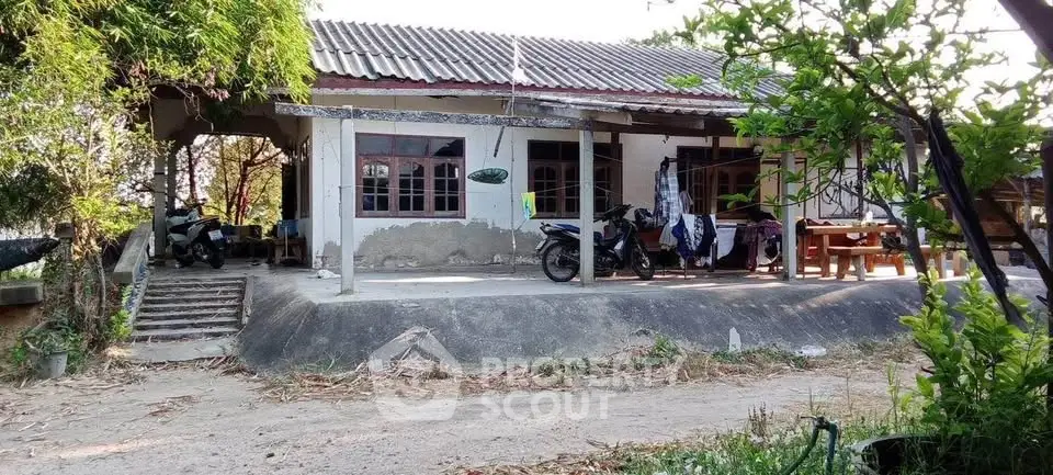 Charming rural house with spacious porch and lush greenery, perfect for serene living.