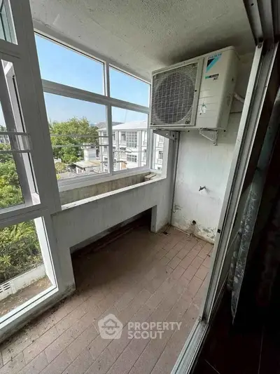 Spacious balcony with large windows and air conditioning unit, offering a serene view of the surroundings.