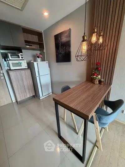Modern kitchen with sleek design, featuring wooden dining table, stylish lighting, and compact appliances.