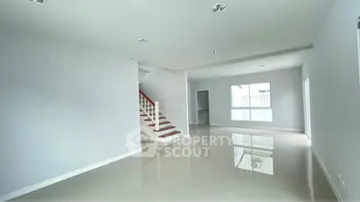 Spacious modern living room with glossy floors and staircase in a bright open layout.