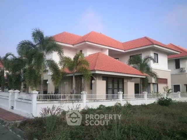 Stunning two-story house with red-tiled roof and lush palm trees