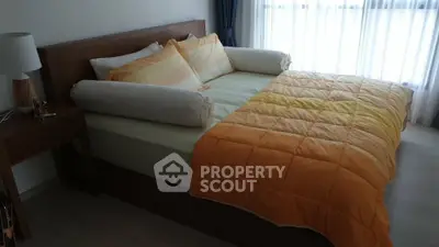 Cozy bedroom with modern decor and natural light, featuring a stylish wooden bed and vibrant orange bedding.