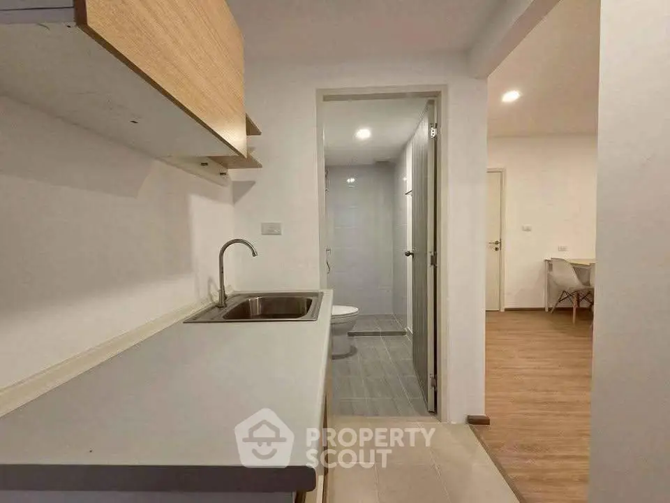 Modern compact kitchen with sleek design and adjacent bathroom in a cozy apartment.